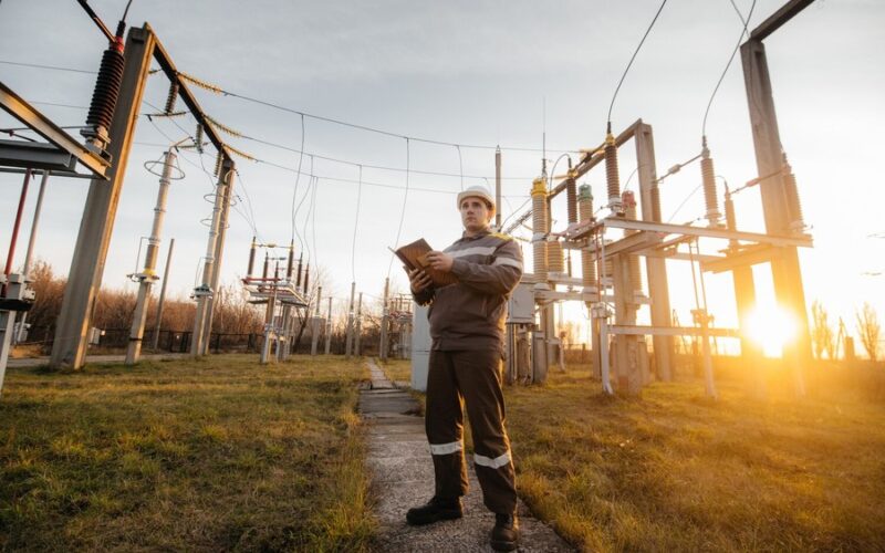 Pracownicy montują słupy energetyczne podczas budowy linii przesyłowej